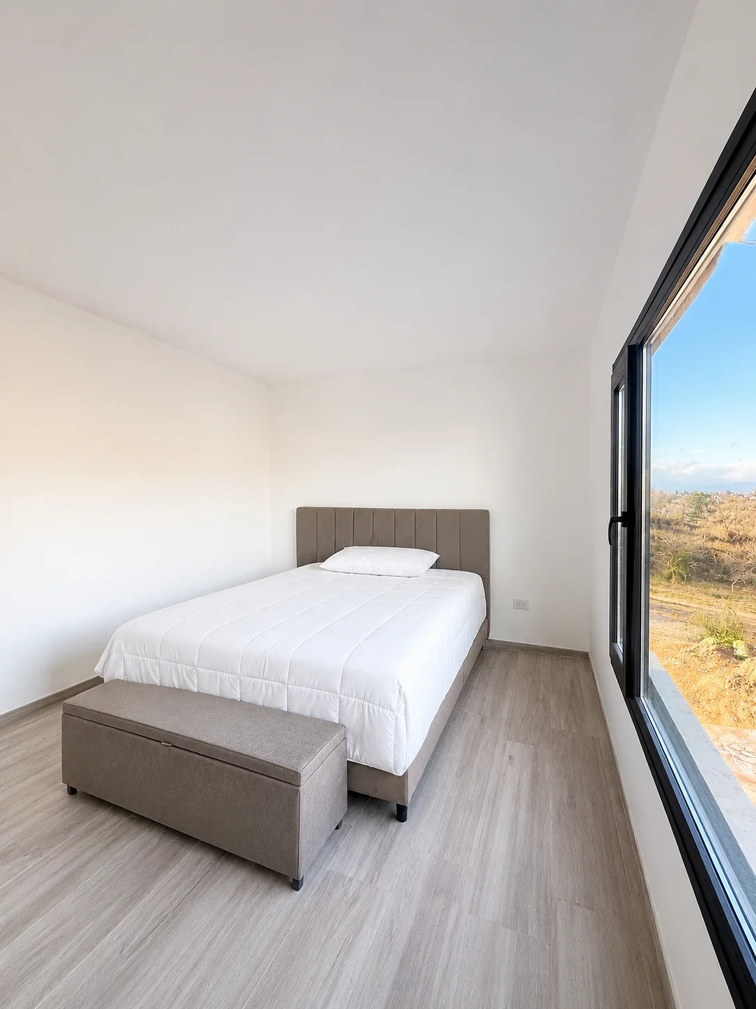 Altos de Carlos Paz — Dormitorio con cama de dos plazas, banqueta al pie y ventana alta al costado