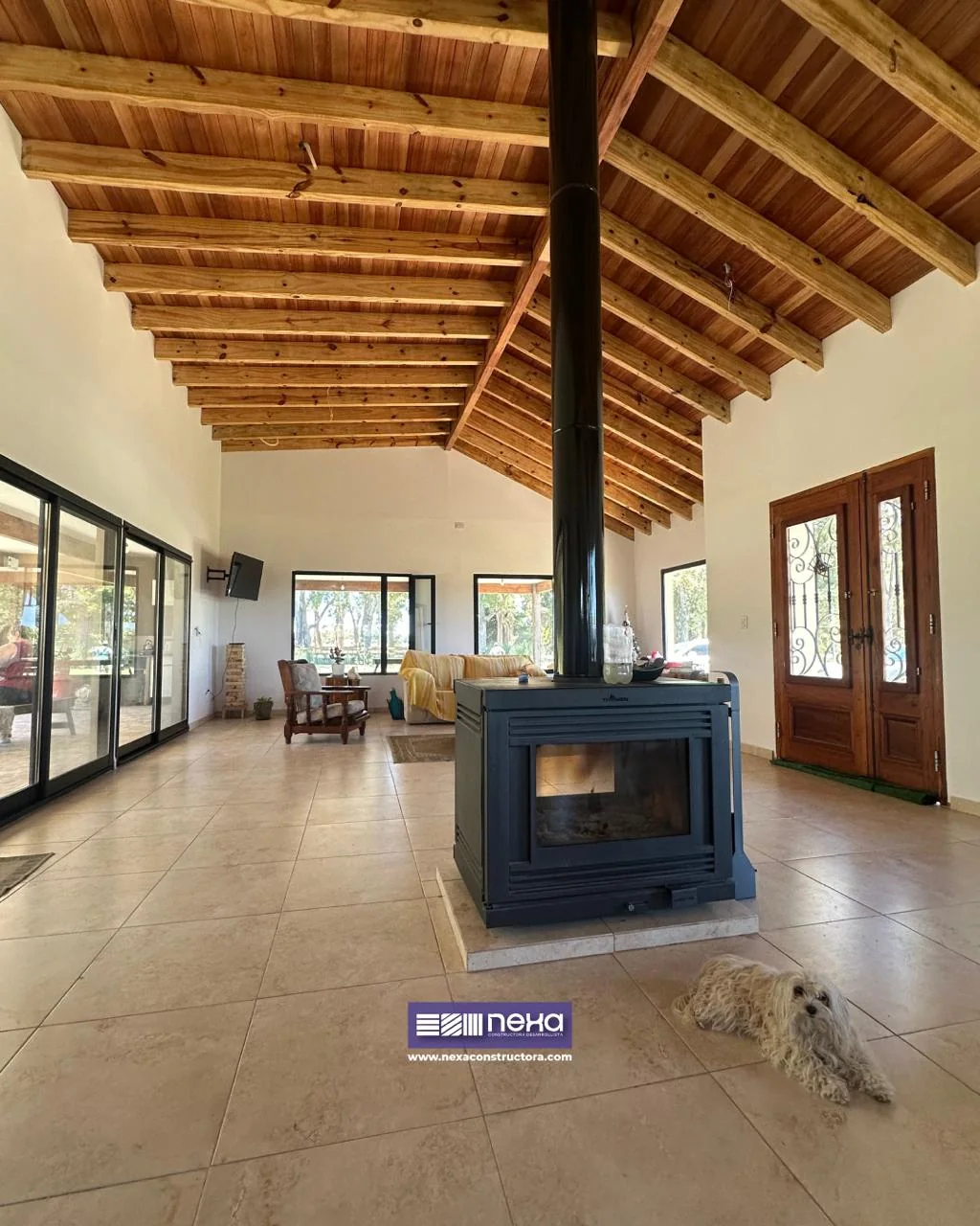 Chacras de San Andrés · Casa 1 — Estar y comedor bajo el techo de madera a dos aguas, con el hogar de doble cara en el medio
