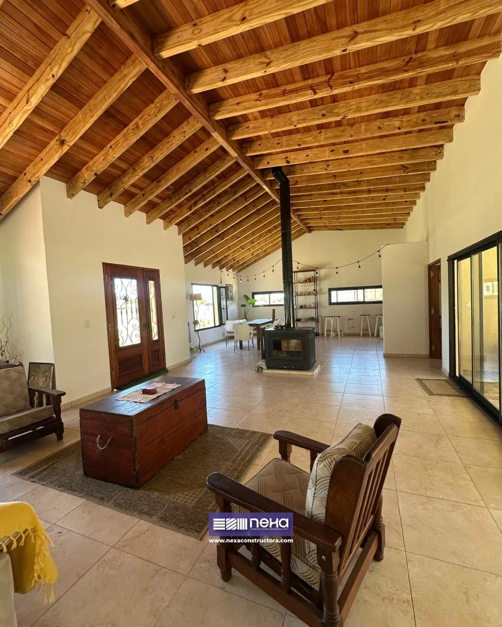 Chacras de San Andrés · Casa 1 — El mismo ambiente desde el otro lado: baúl de madera, sillón y, al fondo, el hogar