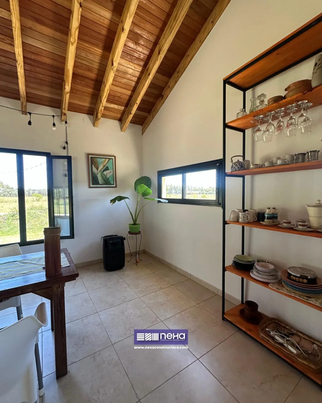 Chacras de San Andrés · Casa 1 — Rincón del comedor con estantería de hierro negro y estantes de madera