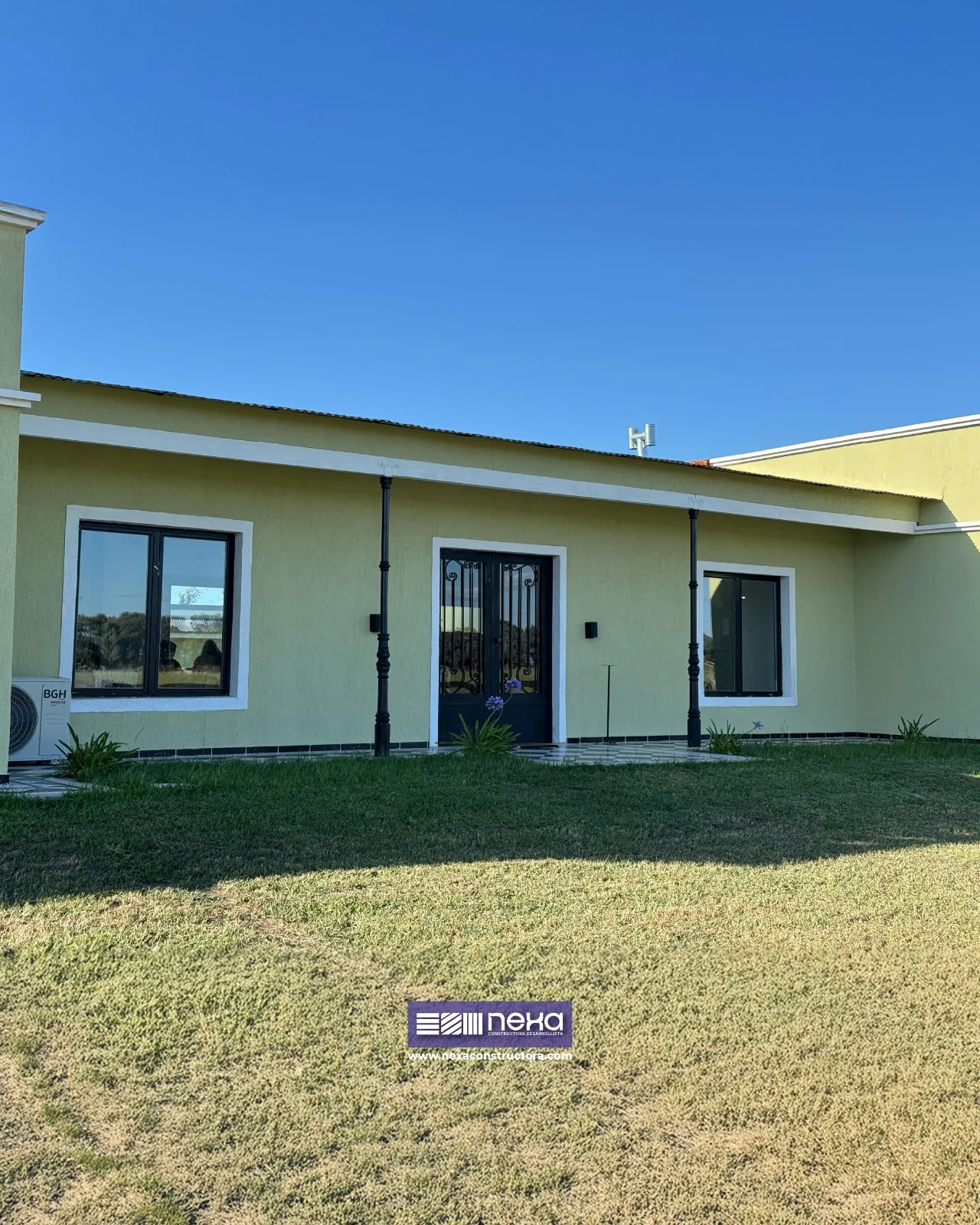 Chacras de San Andrés · Casa 2 — El frente, con la puerta doble de herrería entre dos ventanas y el alero sobre columnas negras