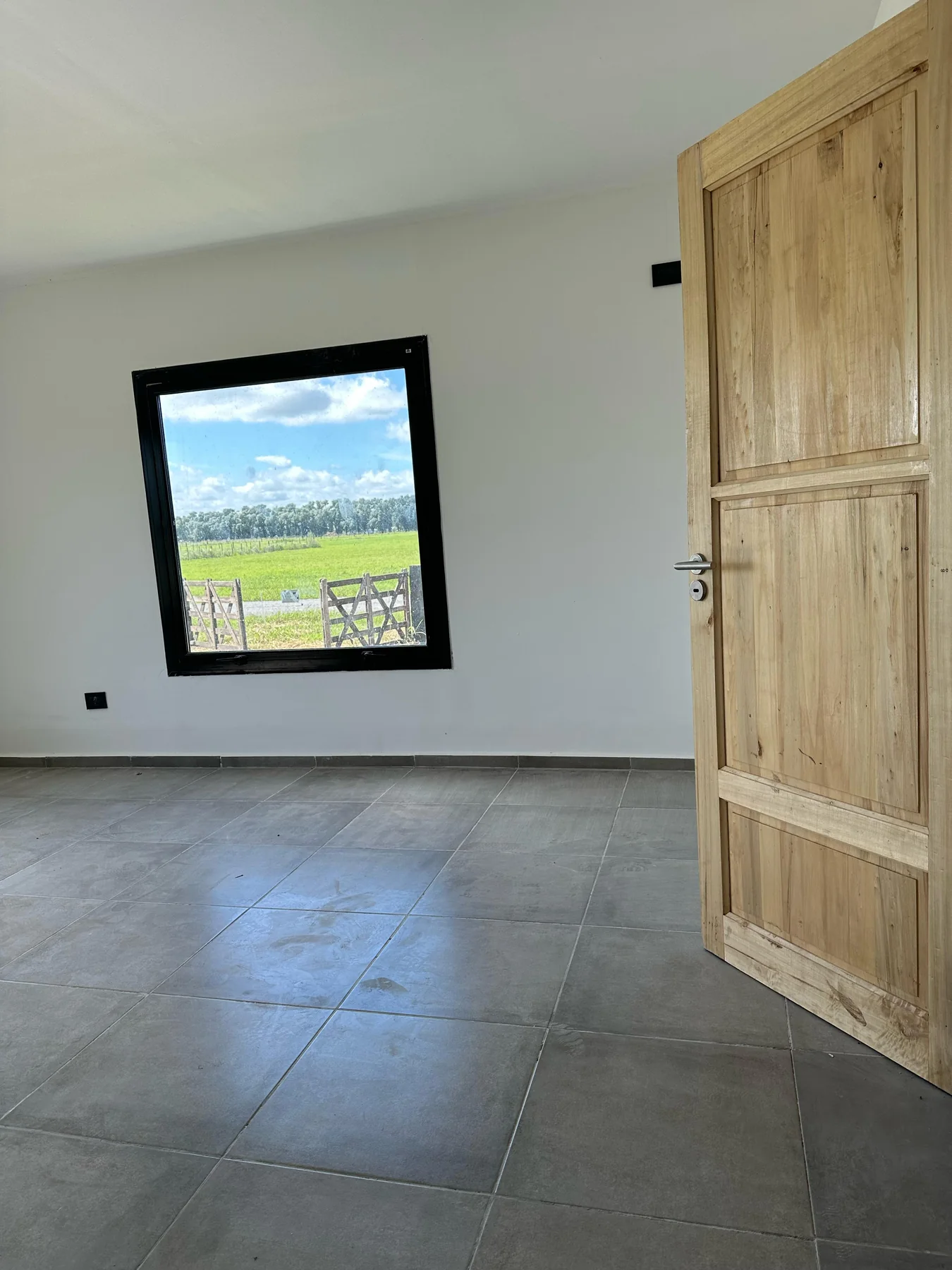 Chacras de San Andrés · Casa 2 — Habitación con ventana de marco negro al campo y puerta de madera maciza