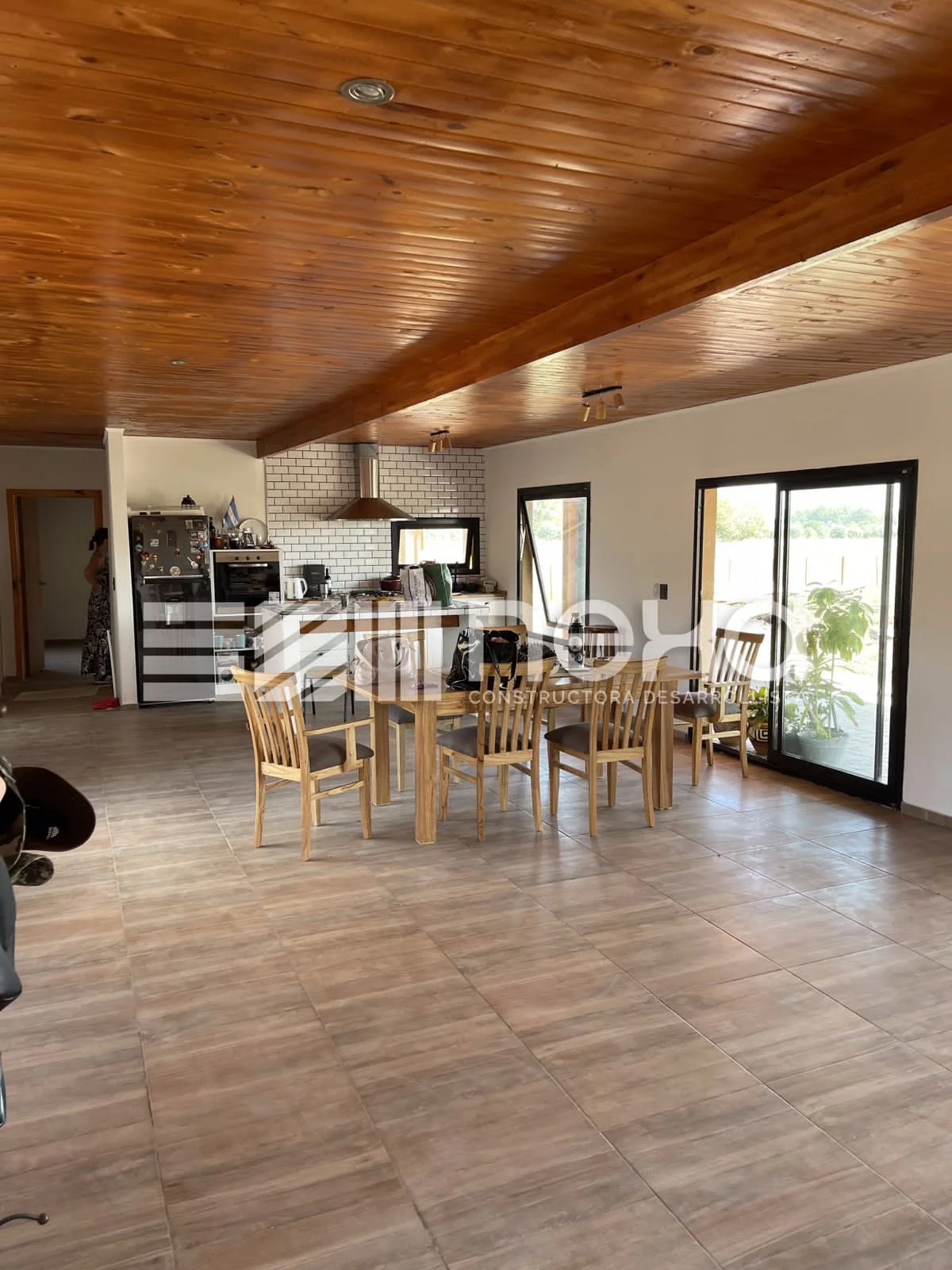 Chacras de San Andrés · Casa 3 — Comedor y cocina en un mismo ambiente, bajo el cielorraso de madera, con ventanales al campo