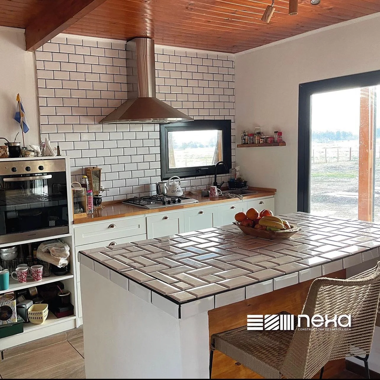 Chacras de San Andrés · Casa 3 — Cocina con revestimiento de azulejos blancos, horno empotrado, campana de acero y barra revestida
