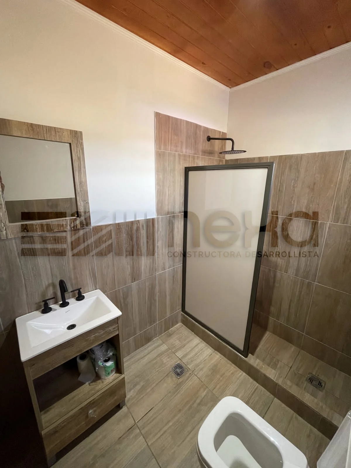 Chacras de San Andrés · Casa 3 — Baño con revestimiento símil madera, vanitory y ducha con mampara