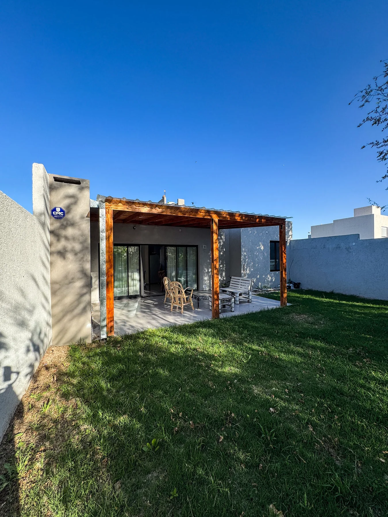 Docta — El contrafrente, con la galería bajo la pérgola de madera y el jardín