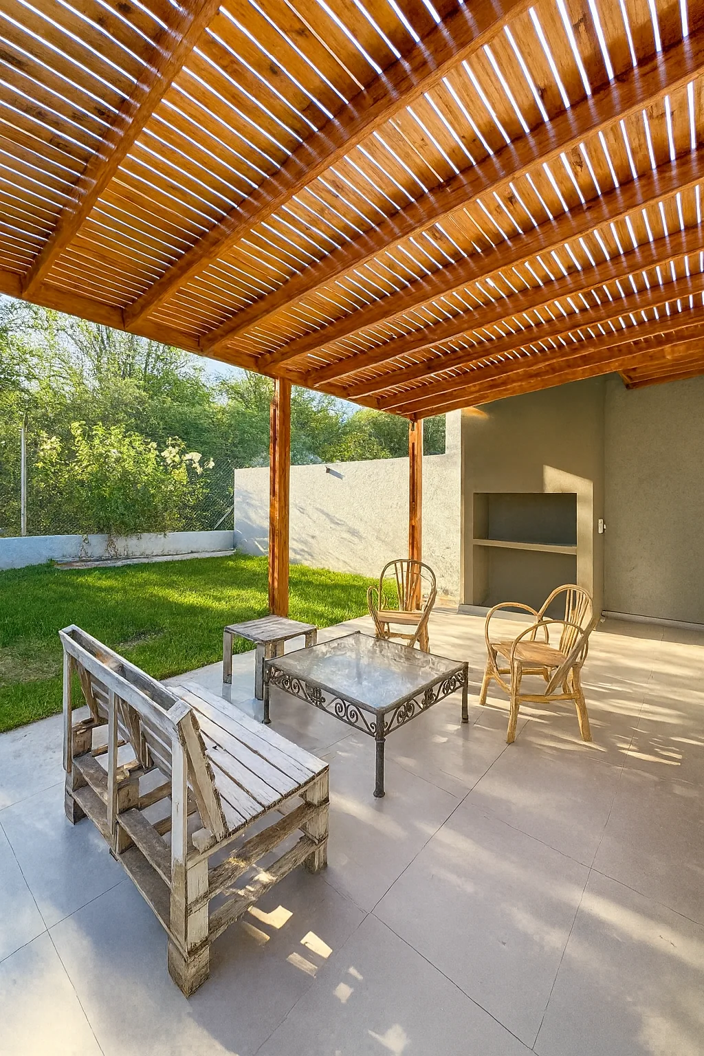 Docta — La galería bajo la pérgola de madera, con la parrilla al fondo