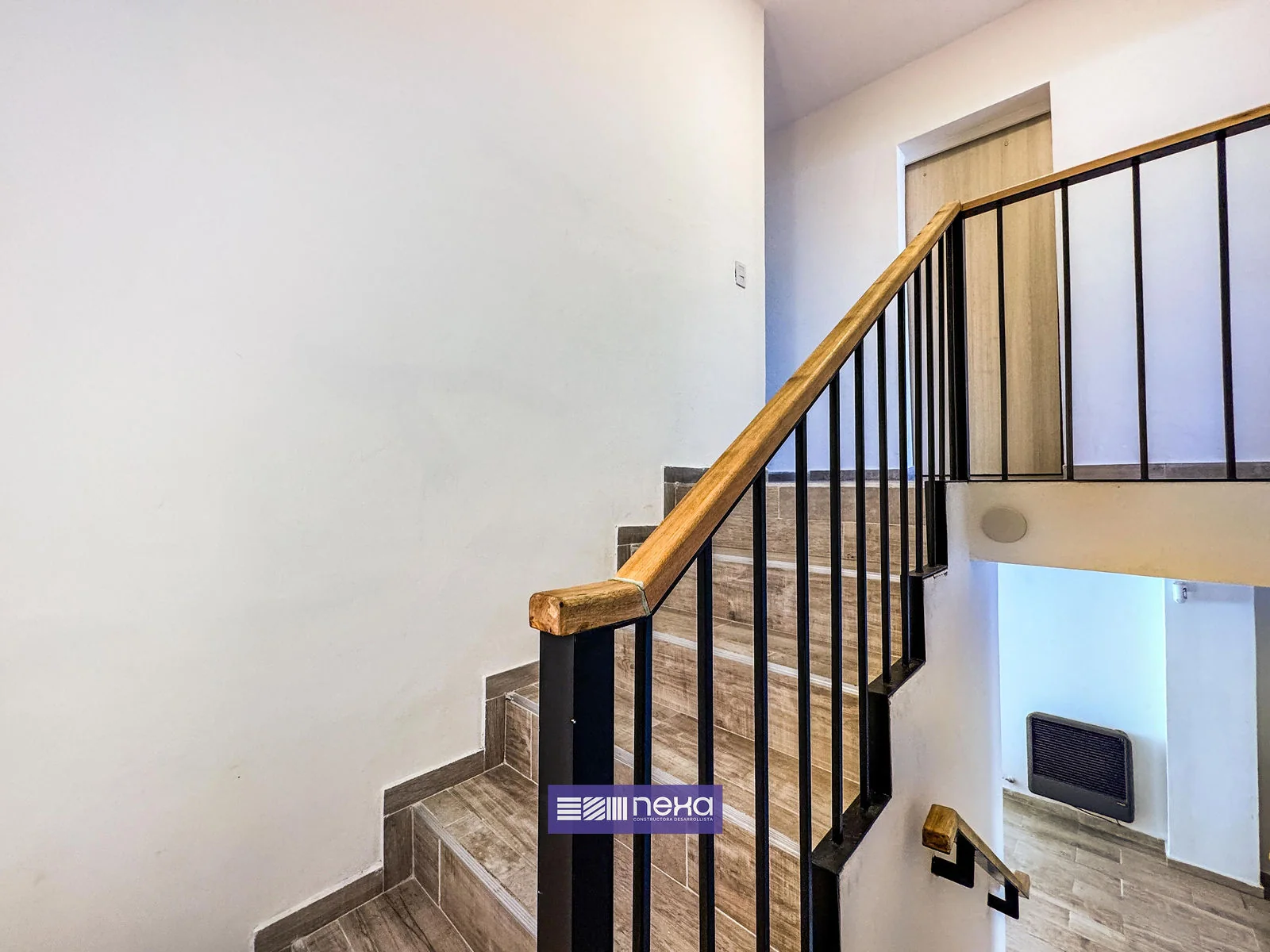 Rincones de Manantiales — Escalera con baranda negra y pasamanos de madera, desde la planta alta