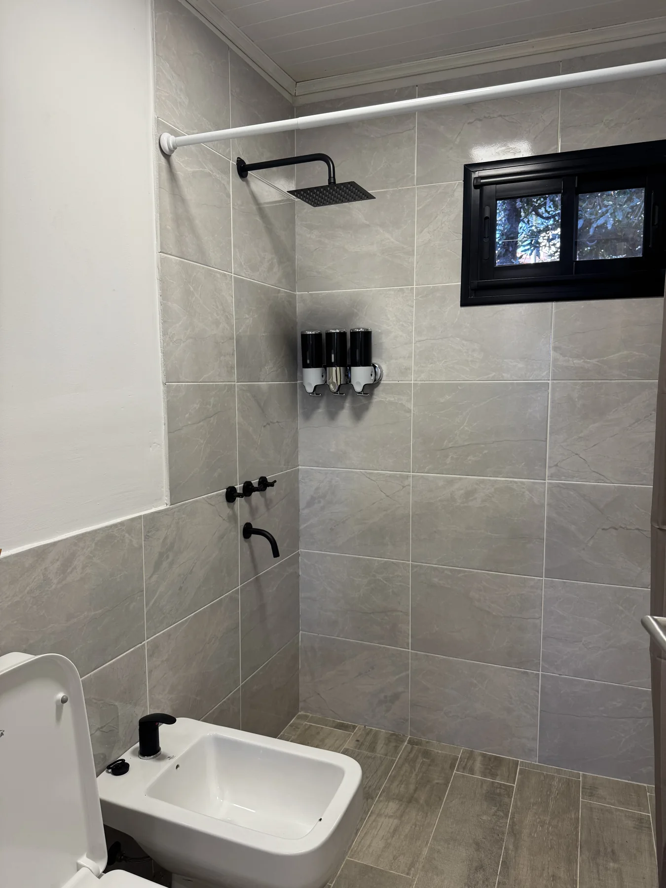 Complejo en La Granja — Baño revestido en gris, con ducha de lluvia negra, bidé y ventana