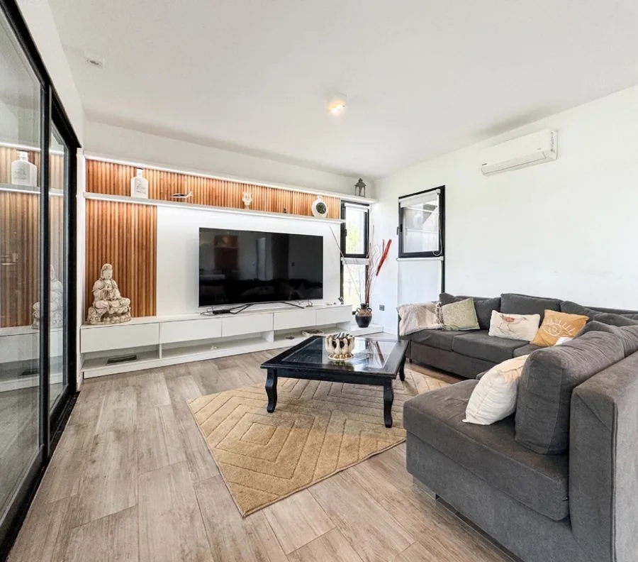 La Melinca Country Golf — El living con el sillón esquinero y el mueble de la tele con listones de madera