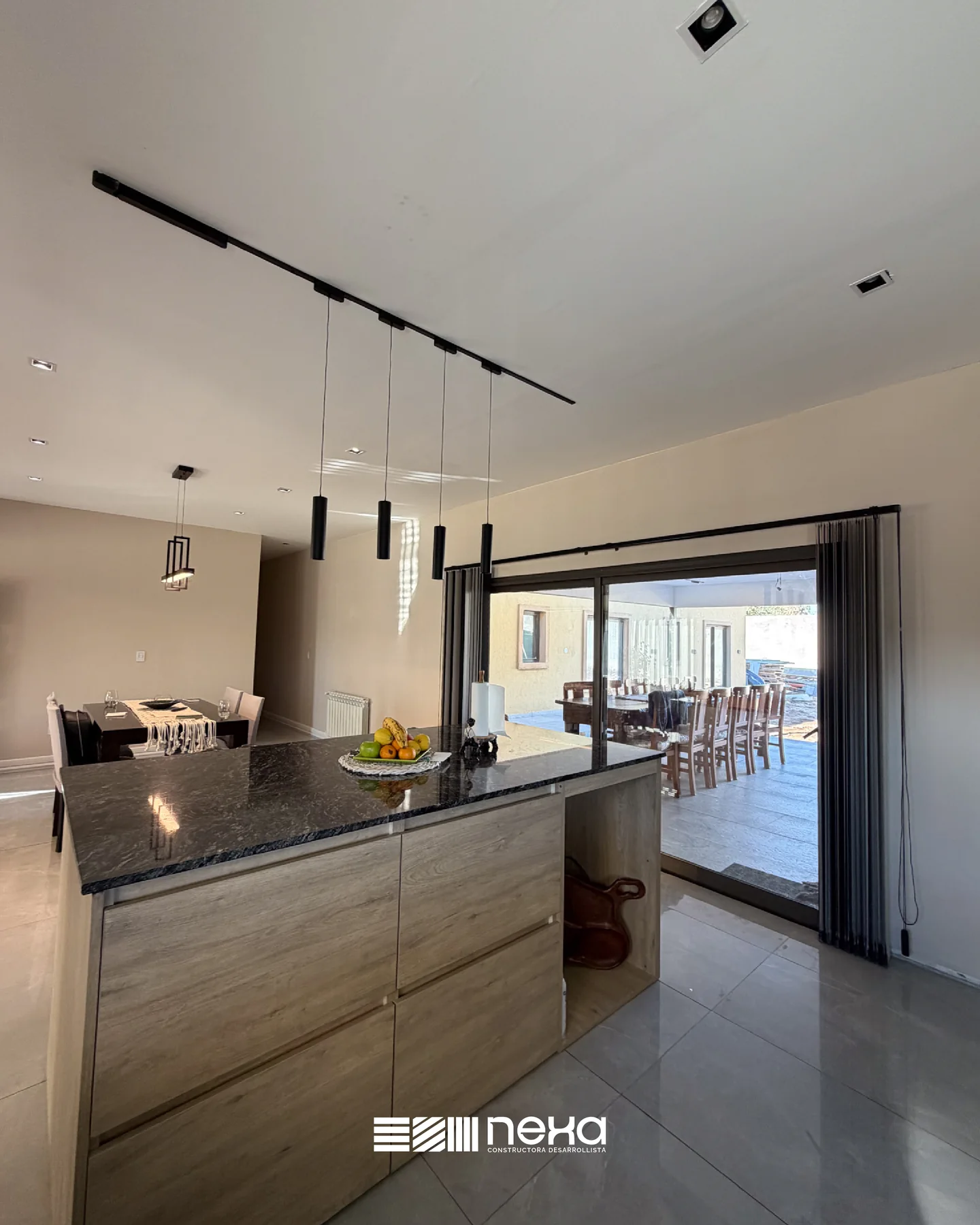 Los Olivos, Guaymallén — Isla de cocina con mesada negra y luces colgantes, abierta al comedor y al ventanal