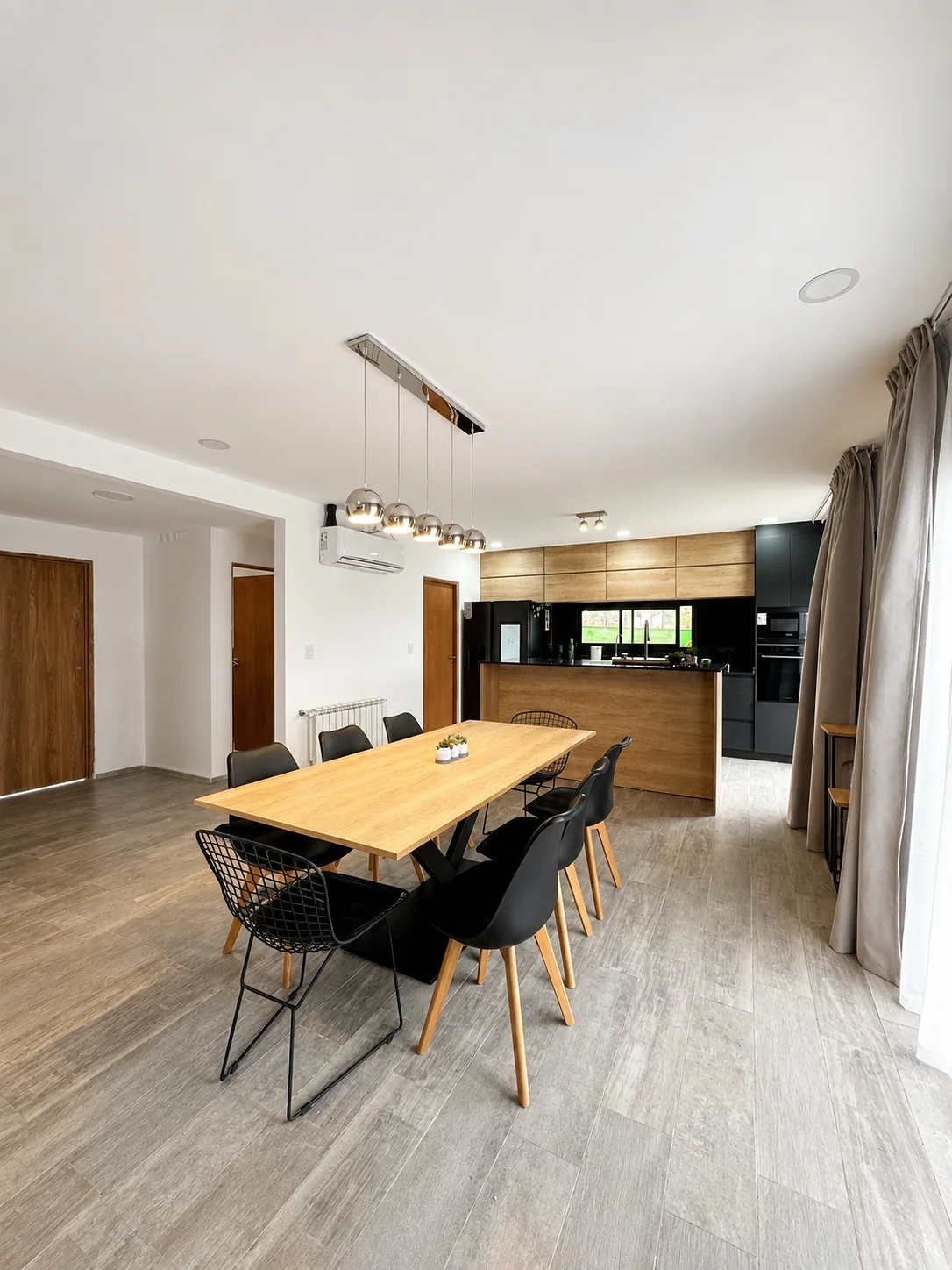 Tejas Cuatro — Comedor con mesa larga de madera y, al fondo, la cocina integrada
