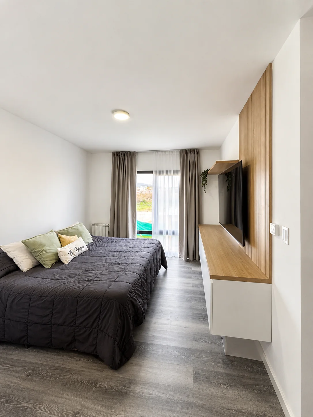 Tejas Cuatro — Dormitorio principal: cama de dos plazas, mueble de TV con panel de listones de madera y ventana al parque