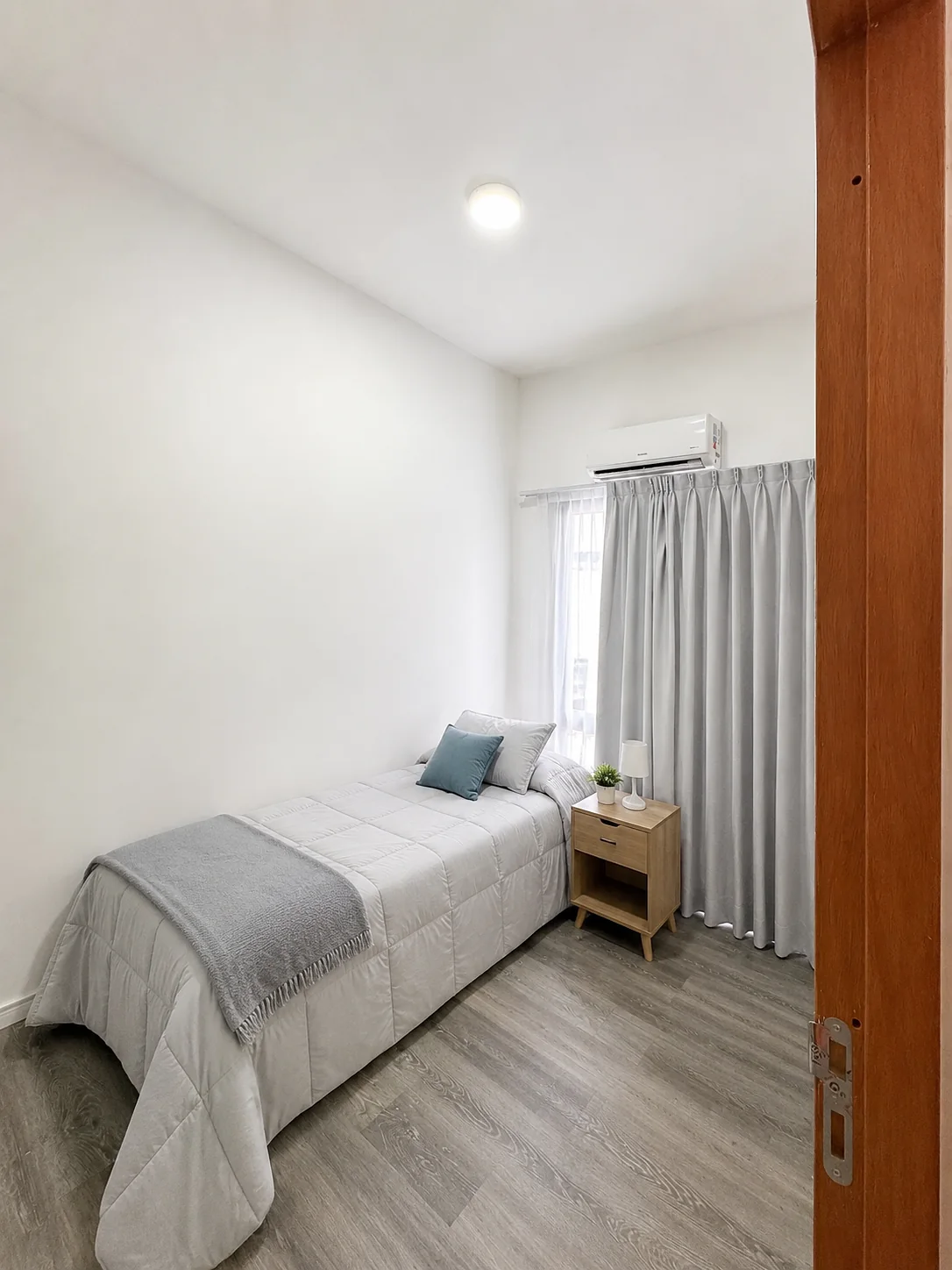 Tejas Cuatro — Dormitorio con cama de una plaza, mesa de luz y aire acondicionado sobre la ventana