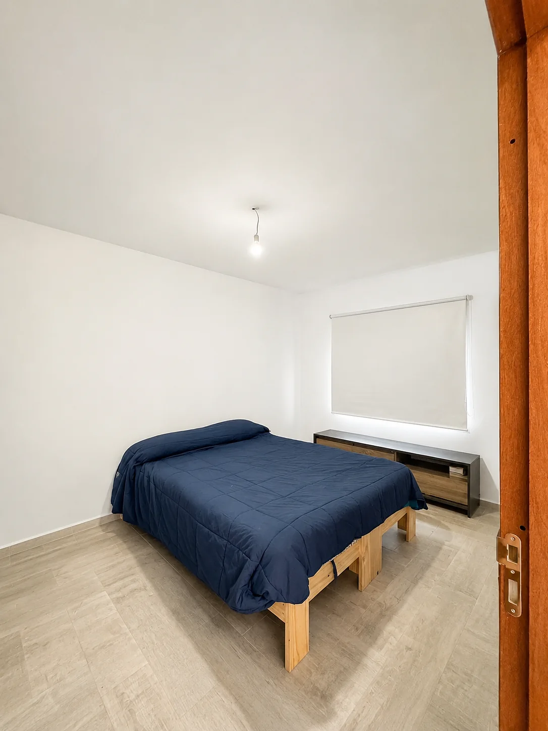 Tejas Cuatro — Dormitorio con cama de dos plazas, cortina de enrollar y mueble bajo
