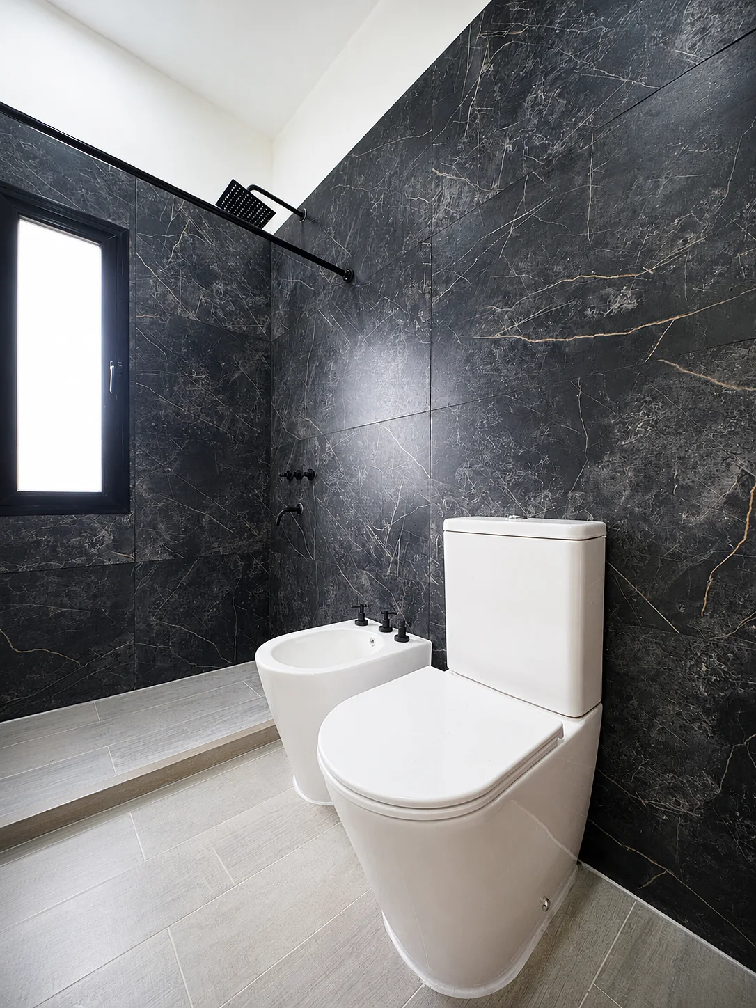 Tejas Cuatro — Baño con revestimiento oscuro veteado: inodoro, bidé y ducha con ventana