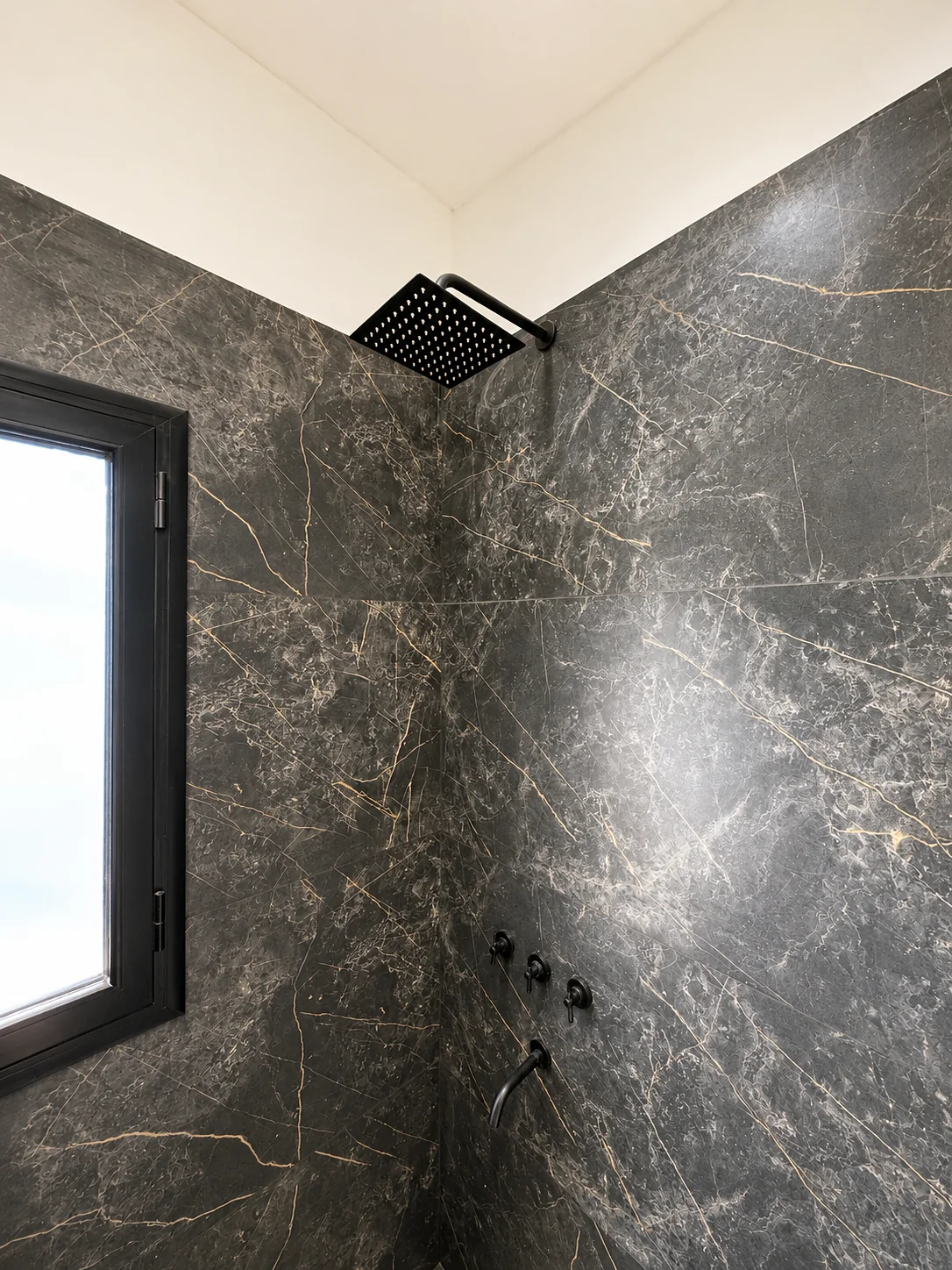Tejas Cuatro — La ducha de ese baño: flor de lluvia negra, grifería negra y ventana