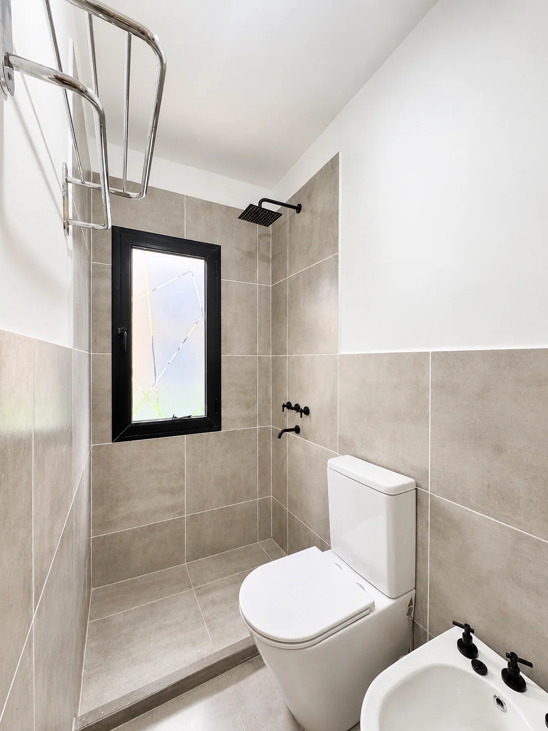 Tejas Cuatro — Baño con revestimiento beige: ducha con ventana, inodoro y bidé