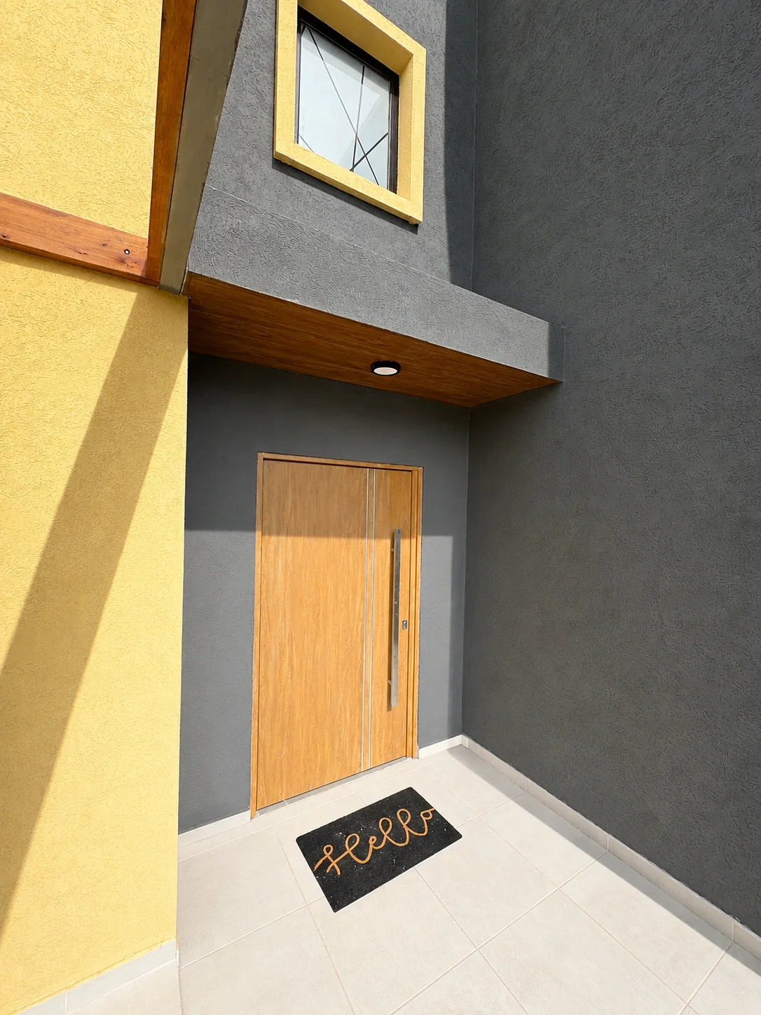 Tejas Cuatro — La puerta de entrada, de madera, bajo un alero gris