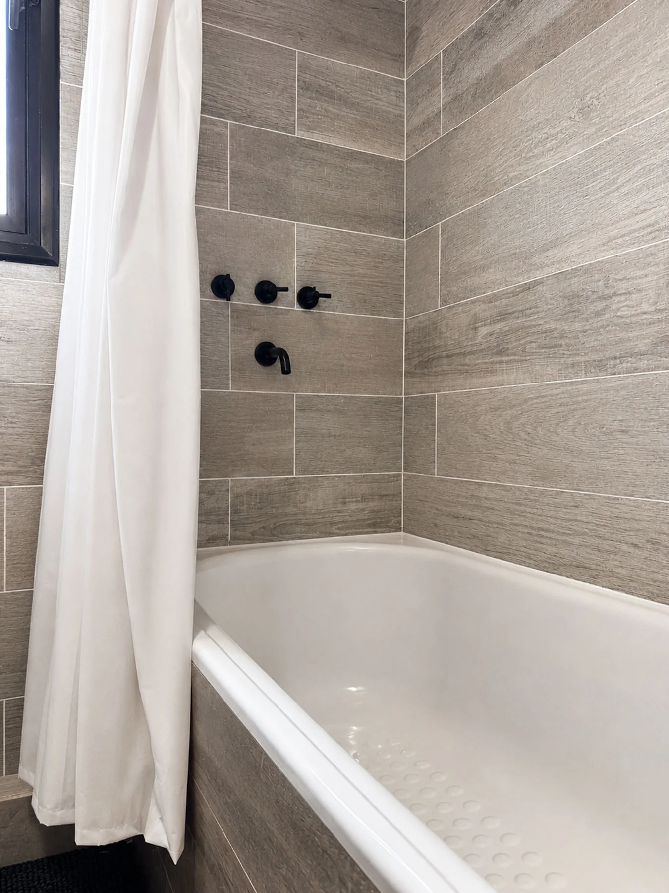 Villa Giardino — Bañera con cortina y grifería negra de pared, en el baño revestido en gris
