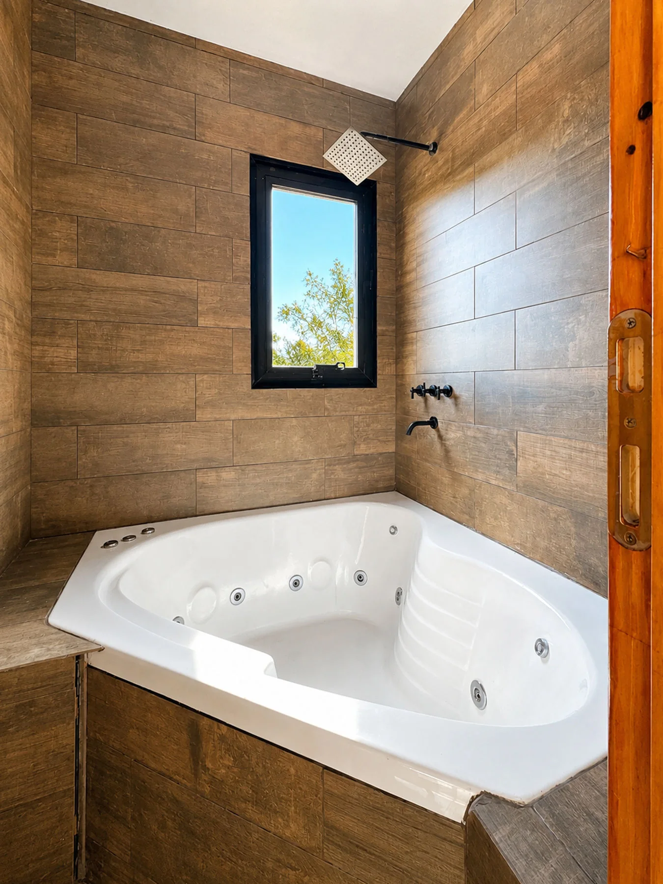 Villa Giardino — Hidromasaje esquinero con ducha de lluvia y ventana, con revestimiento símil madera