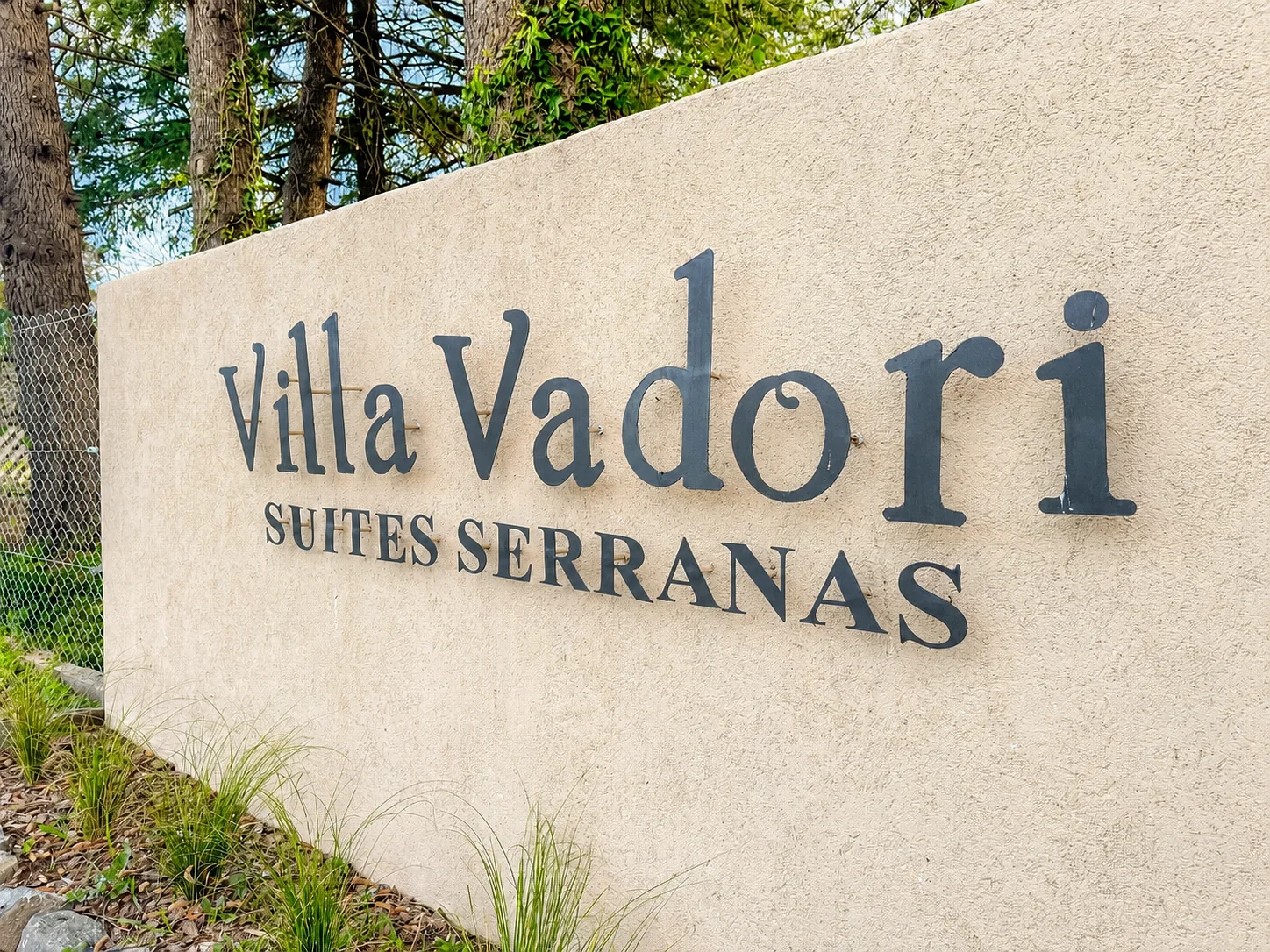 Villa Vadori · Suites Serranas — Cartel de entrada con el nombre Villa Vadori Suites Serranas