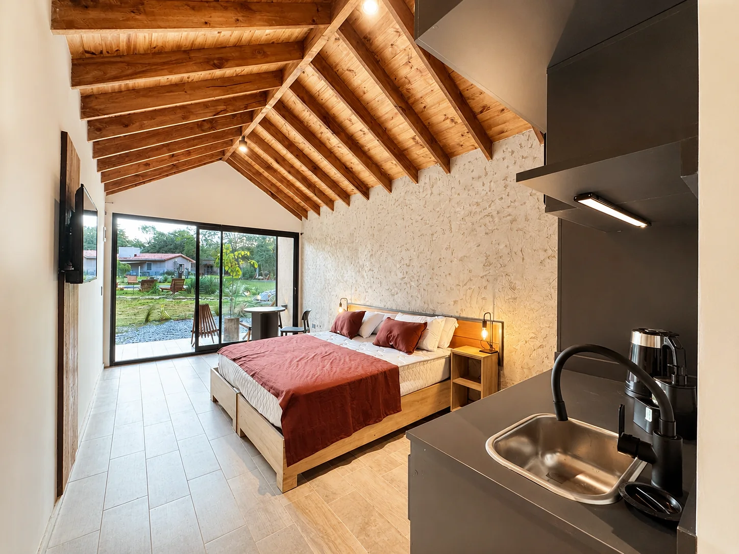 Villa Vadori · Suites Serranas — La misma suite vista desde la kitchenette, hacia la cama y el ventanal