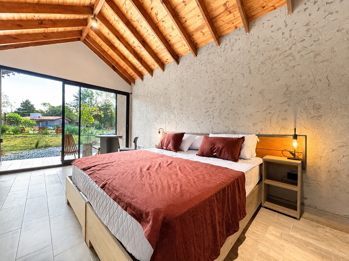Villa Vadori · Suites Serranas — La cama de la suite frente al ventanal corredizo
