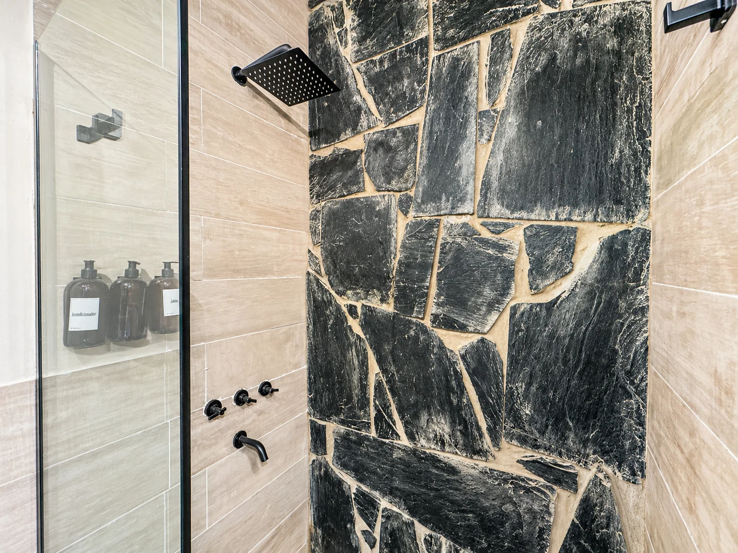 Villa Vadori · Suites Serranas — Ducha con pared de piedra, grifería negra y lluvia cuadrada