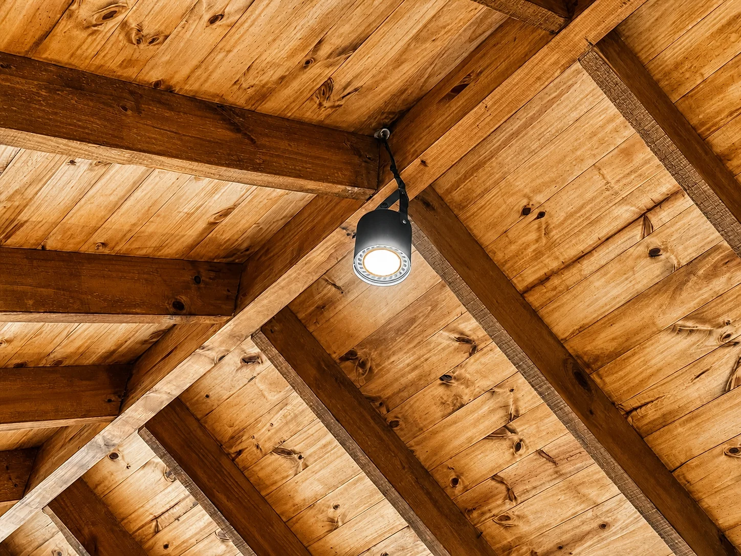 Villa Vadori · Suites Serranas — Detalle del techo: machimbre y tirantes de madera con un spot